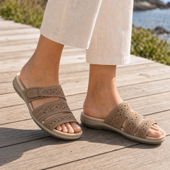 Mujer caminando con sandalias ortopédicas marrones de velcro en un paseo soleado