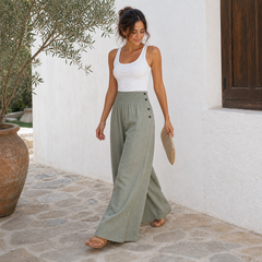 Mujer con pantalón ancho de lino verde salvia caminando en patio mediterráneo