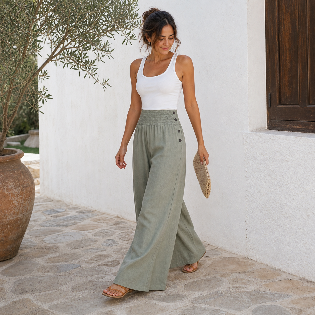 Mujer con pantalón ancho de lino verde salvia caminando en patio mediterráneo