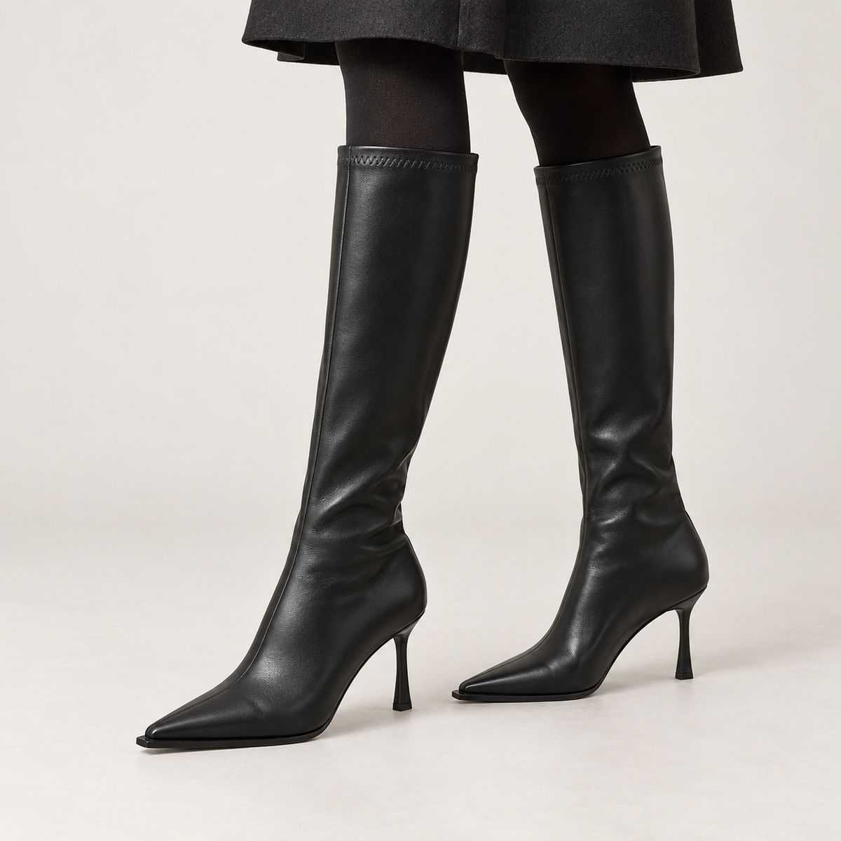 Botas altas negras de tacón de aguja puestas con media opaca