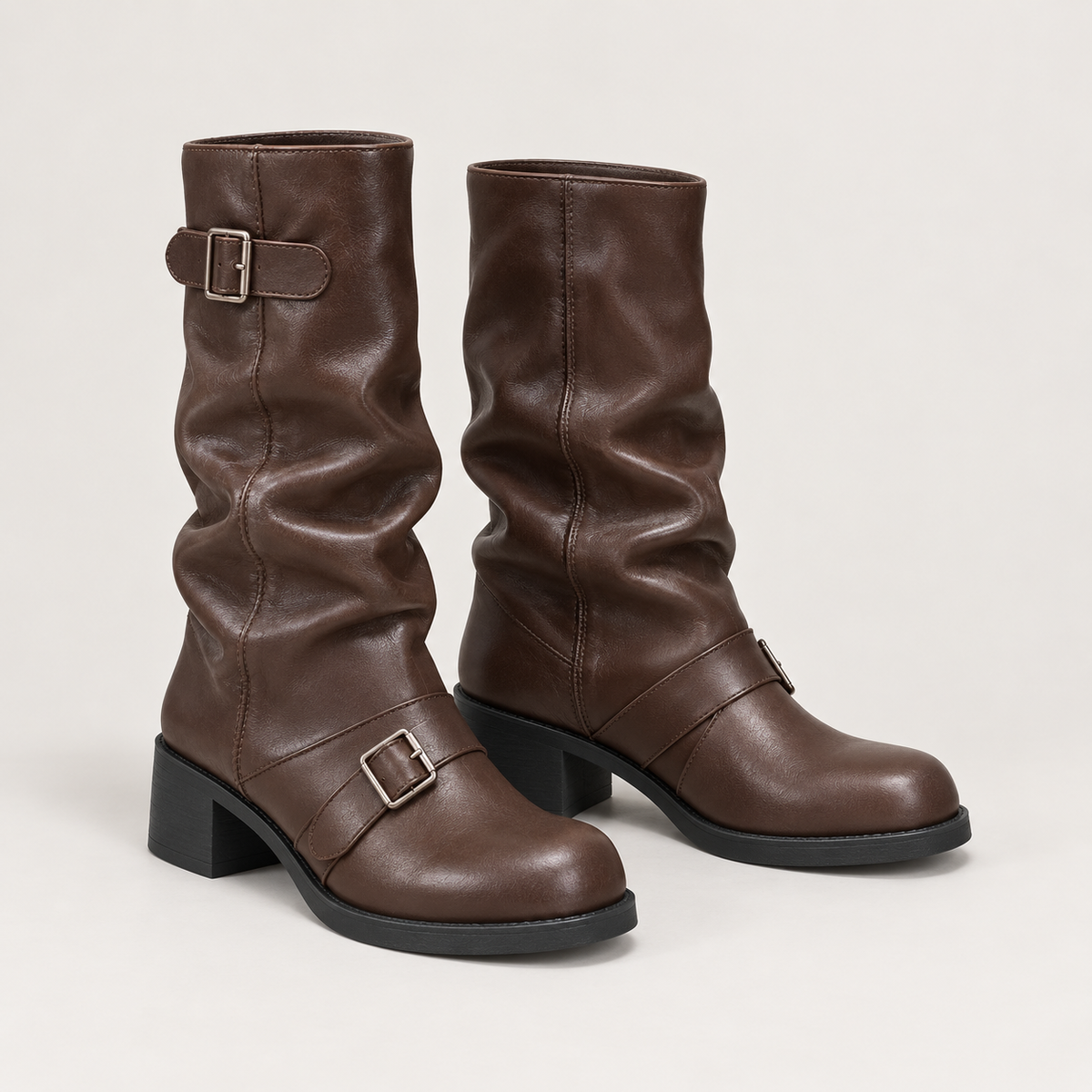 Botas moteras marrones fruncidas con hebillas en estudio