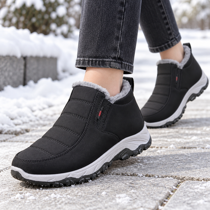 Botas de nieve negras de perfil con suela antideslizante en calle de invierno