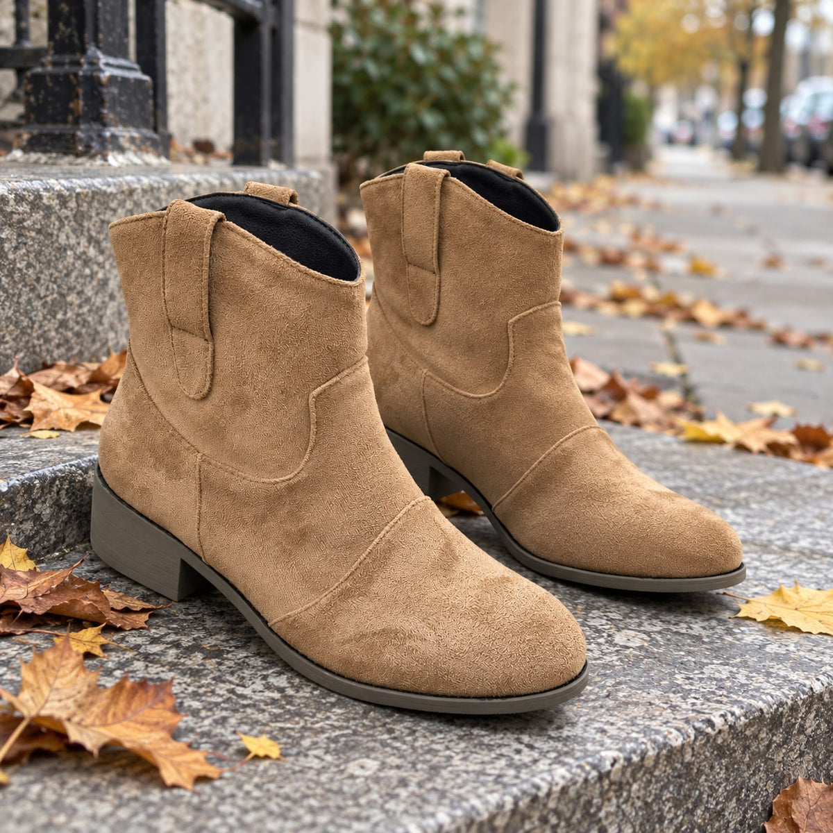 Botines cowboy camel de efecto ante sobre un escalón de piedra con hojas