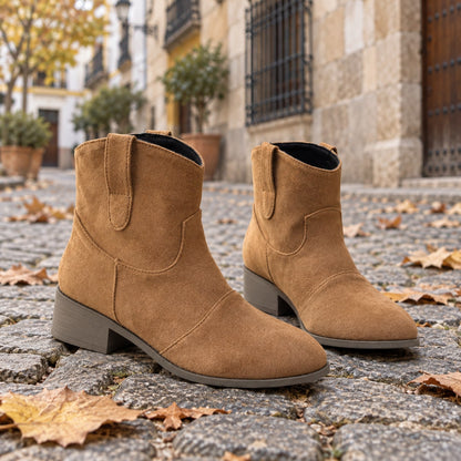 Botines cowboy marrones de efecto ante sobre adoquines con hojas de otoño