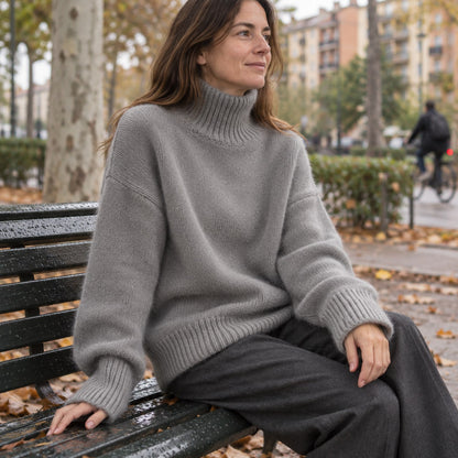 Jersey oversize de cuello alto gris sentado en un banco de ciudad