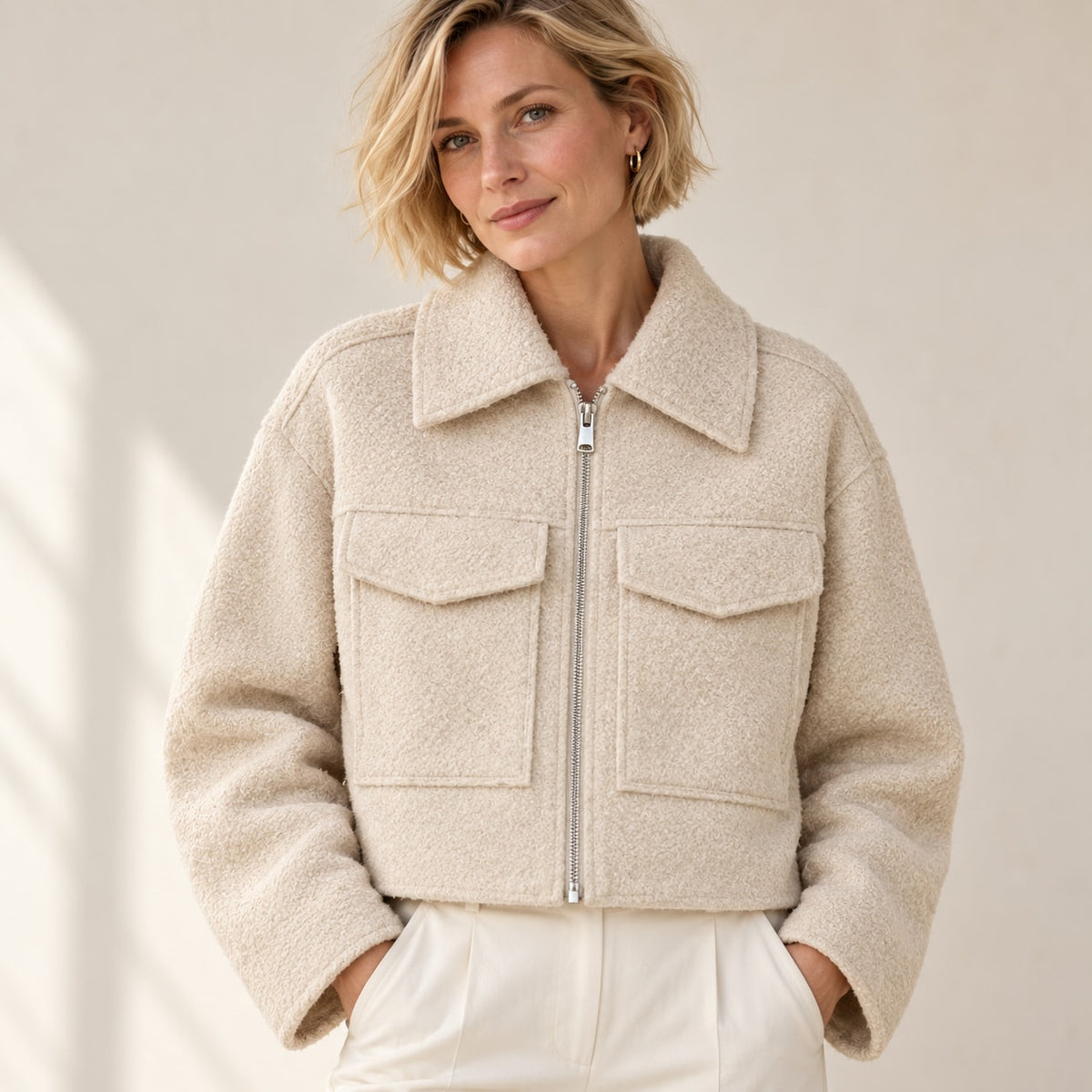 Detalle frontal de chaqueta corta beige bouclé con bolsillos