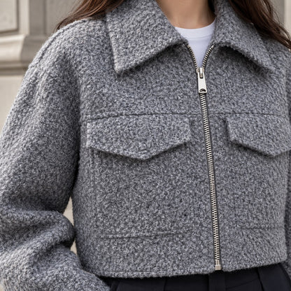 Detalle de textura bouclé, cremallera y bolsillo de chaqueta gris