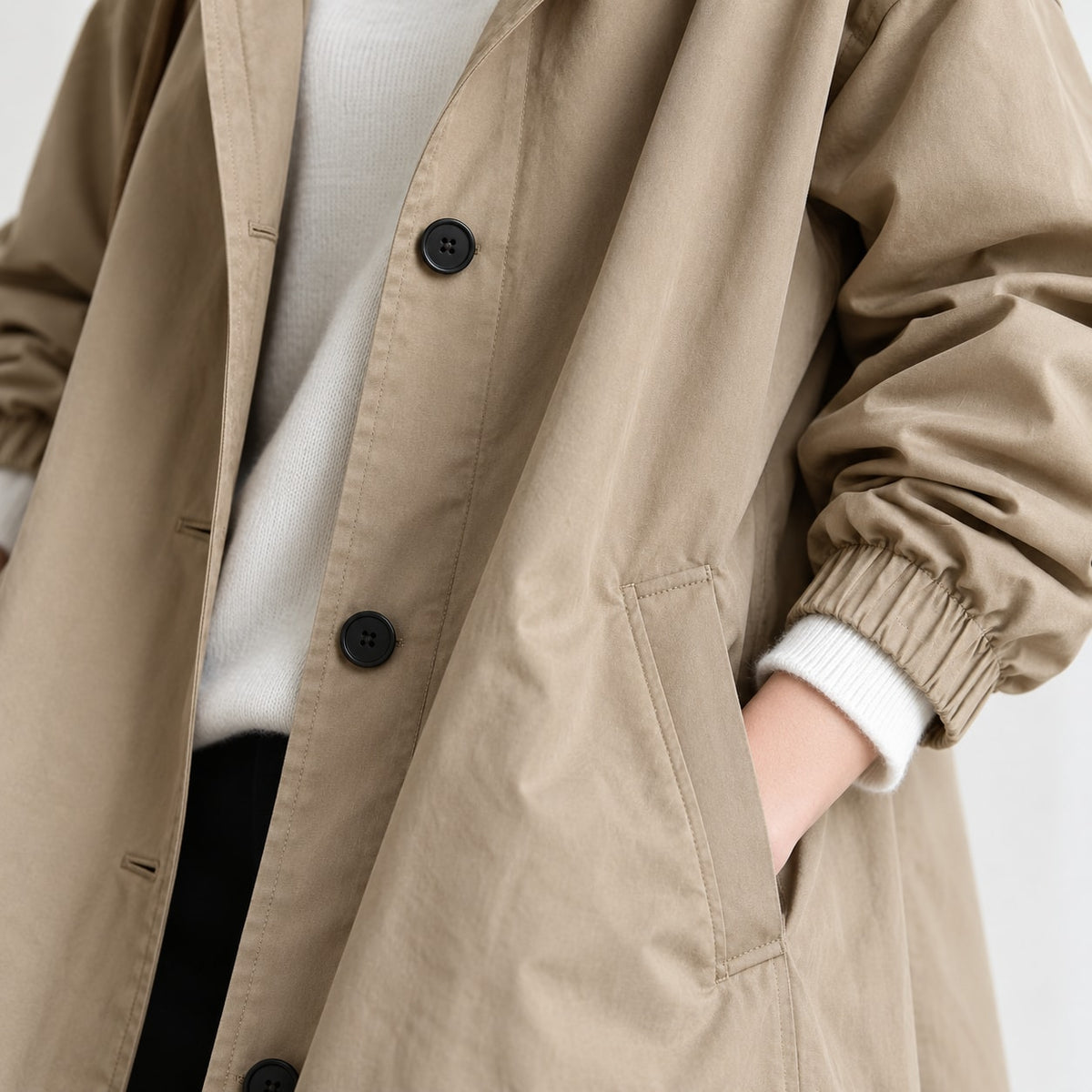 Primer plano del tejido de gabardina beige, bolsillo y botones negros
