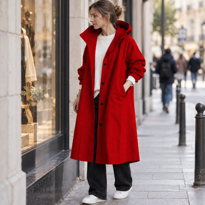 Gabardina larga roja con capucha, look de otoño junto a escaparate