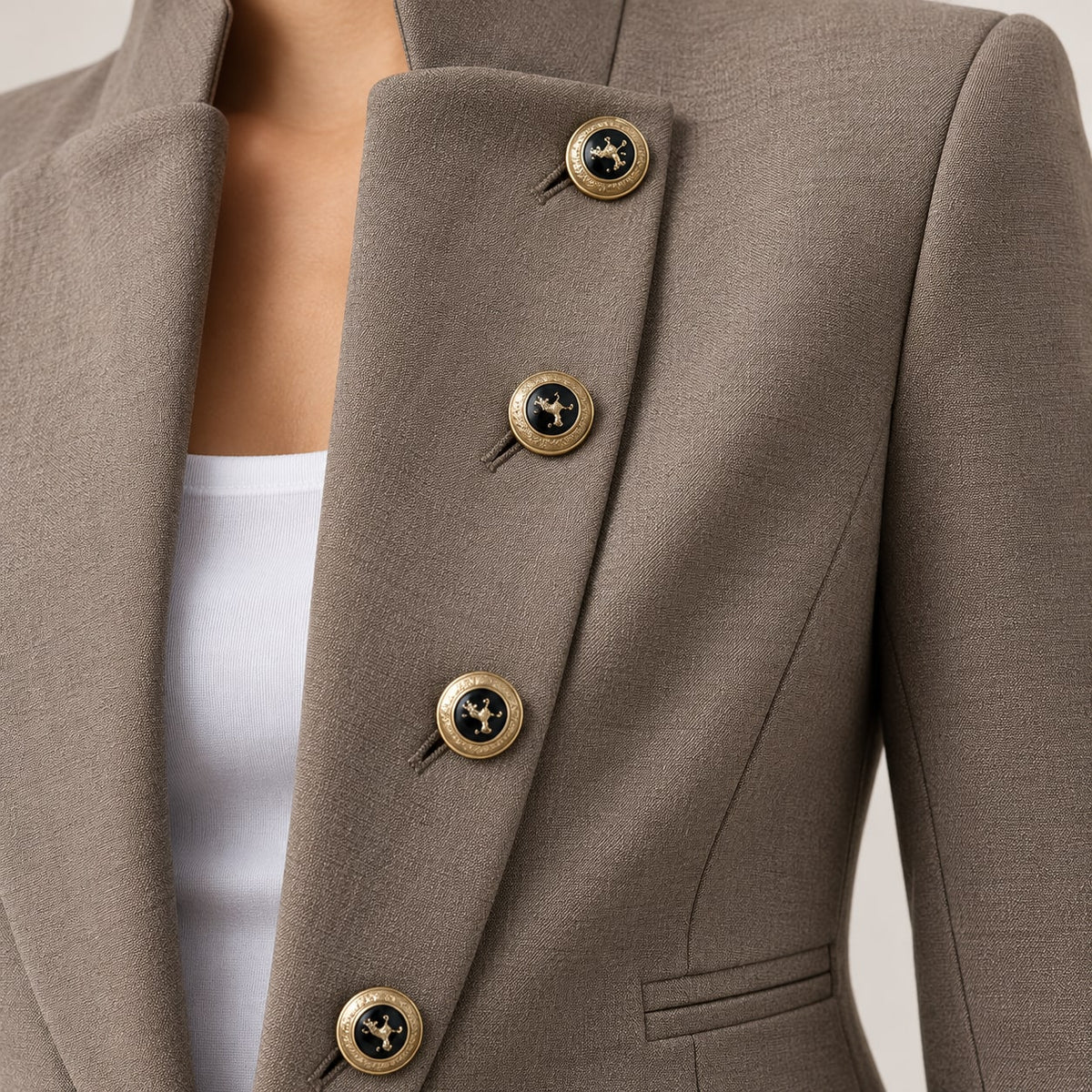 Primer plano del tejido topo y los botones dorados del blazer militar