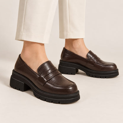 Mocasines marrones de plataforma puestos con pantalón claro en estudio