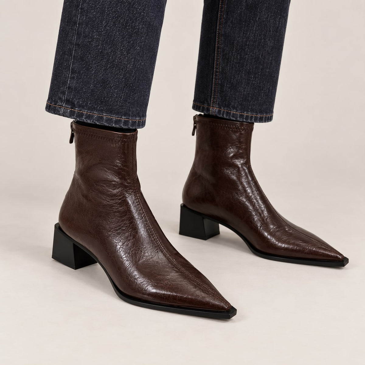 Botines marrones de punta fina puestos con vaquero oscuro en estudio