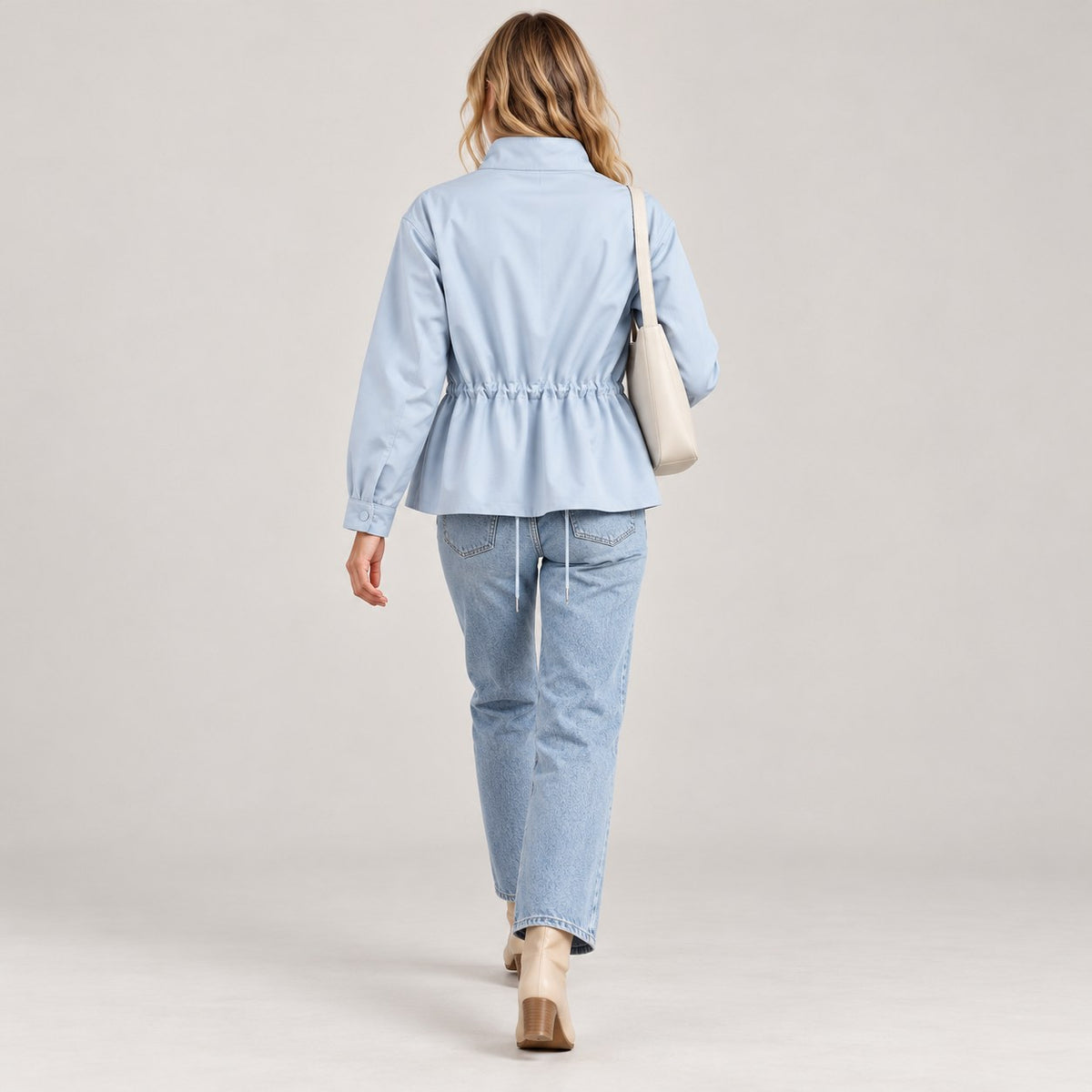 Chaqueta entretiempo azul claro de espaldas caminando, peplum y cordón