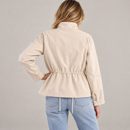 Chaqueta entretiempo beige de espaldas con la mano en la cadera