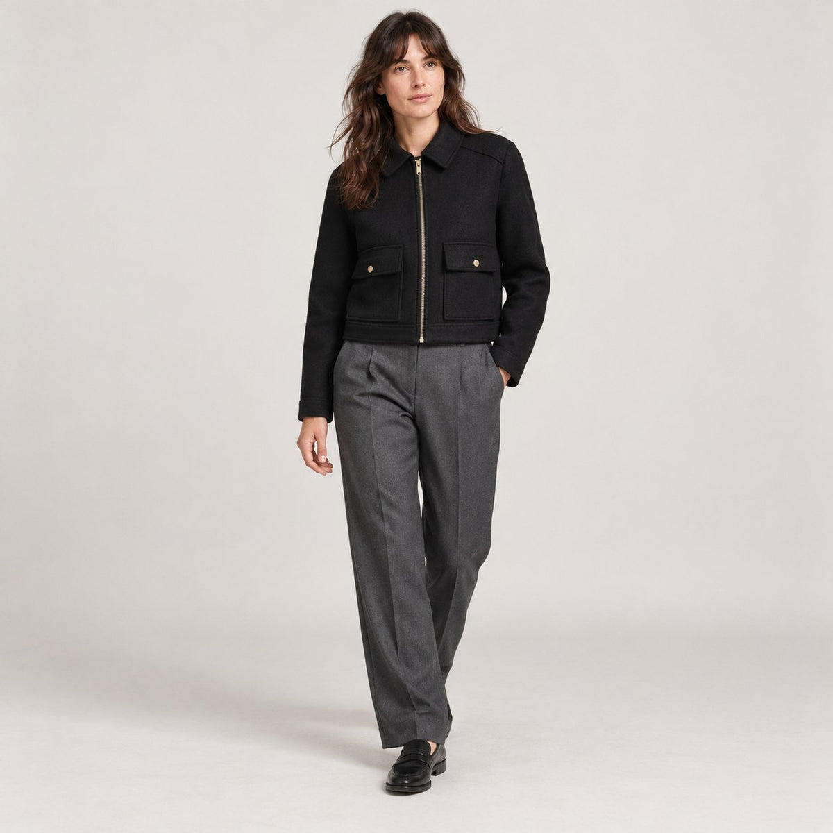 Chaquetón corto negro caminando con pantalón gris