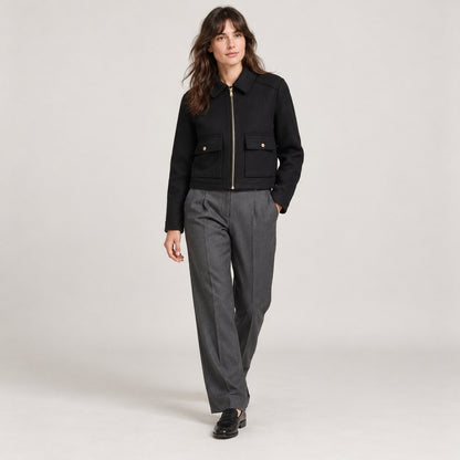 Chaquetón corto negro caminando con pantalón gris