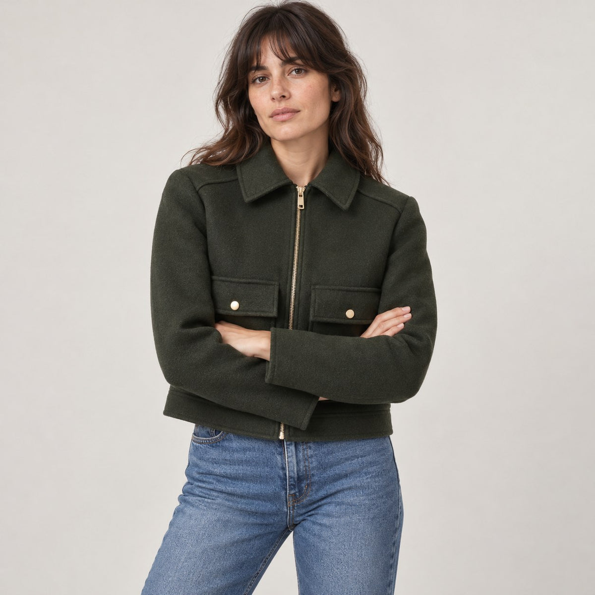 Chaquetón corto verde oscuro con los brazos cruzados