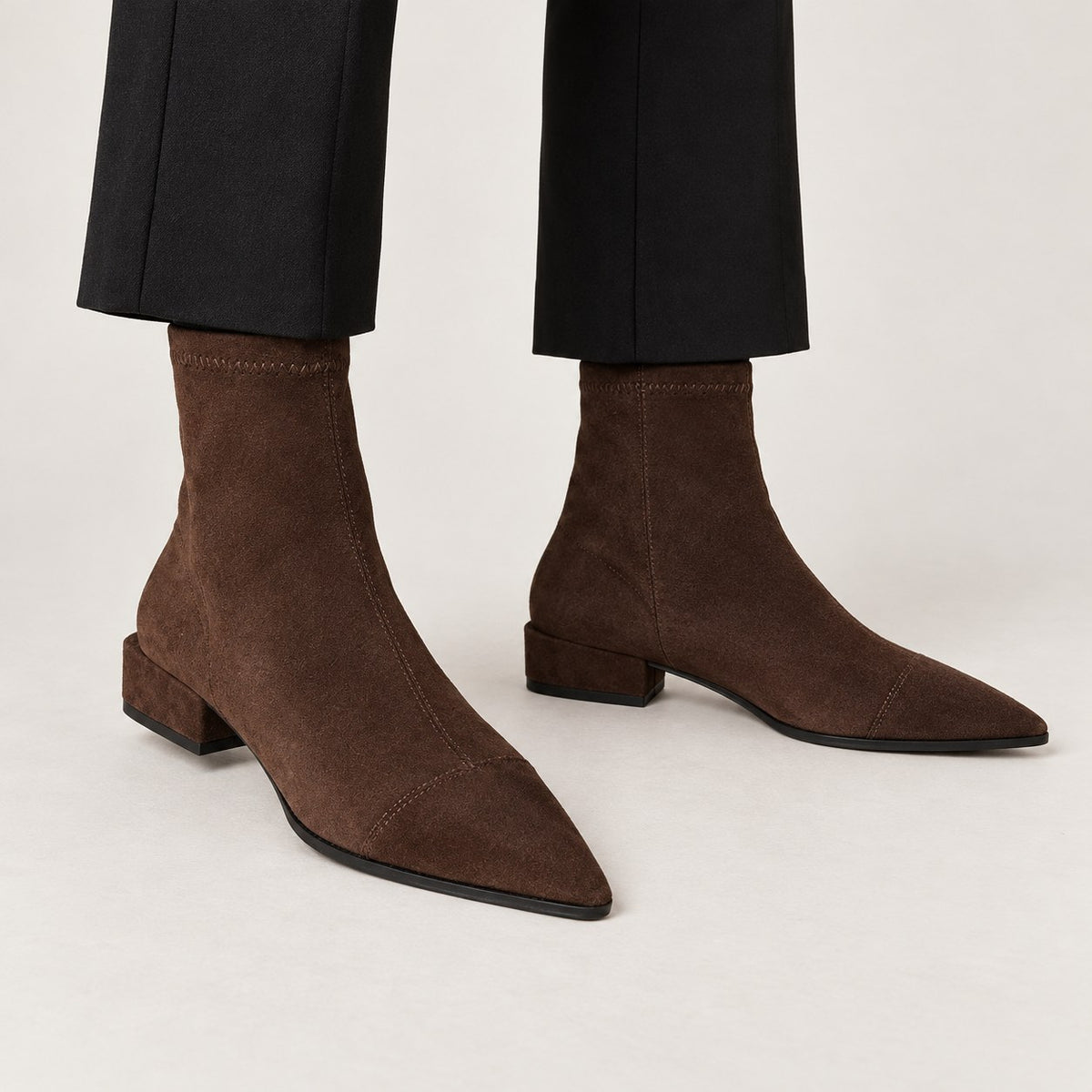 Botines de ante marrones puestos con pantalón negro tobillero
