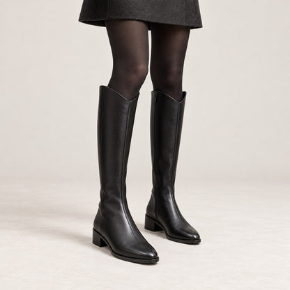 Botas altas negras puestas con medias y falda corta