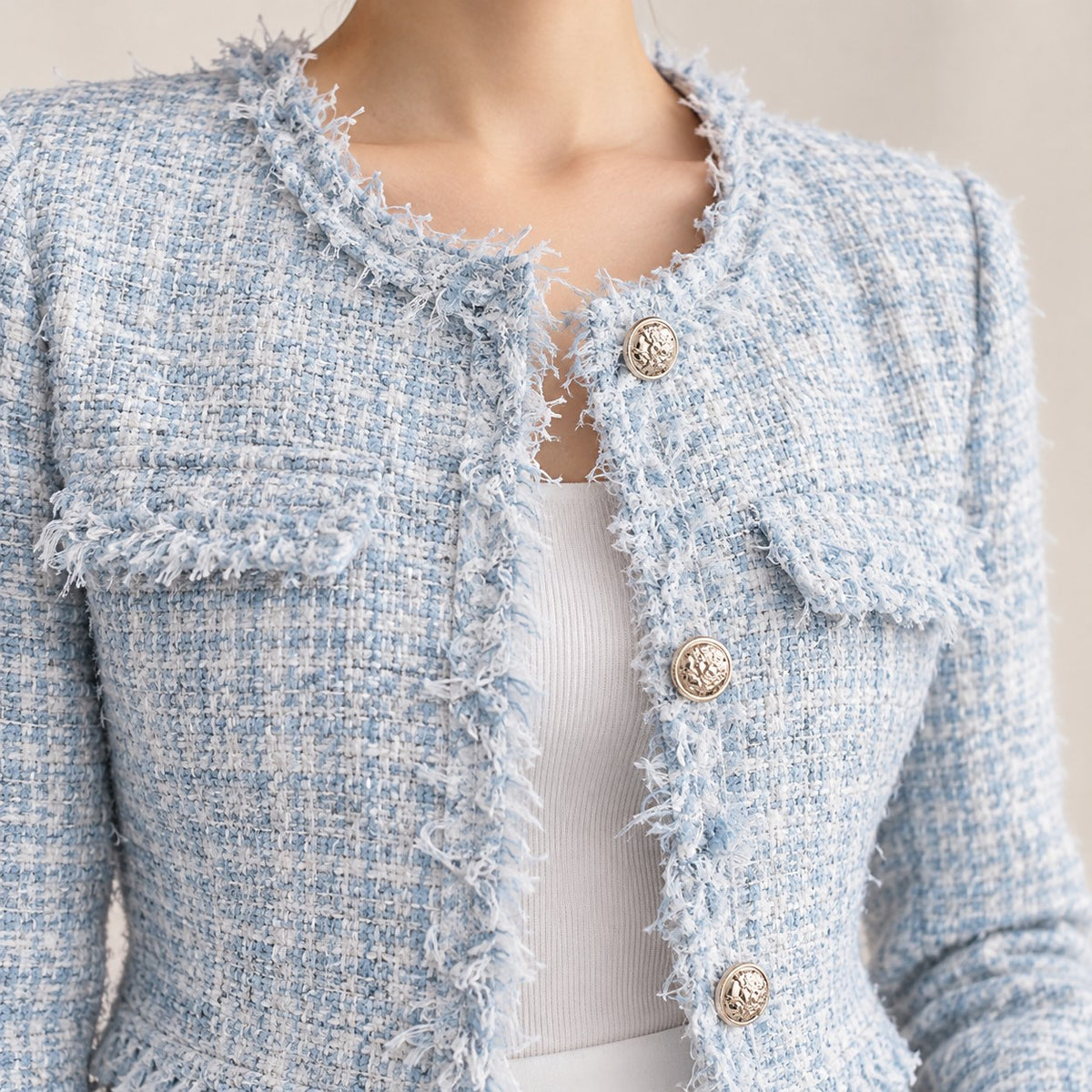 Detalle de los flecos, los bolsillos y los botones dorados de la chaqueta tweed azul
