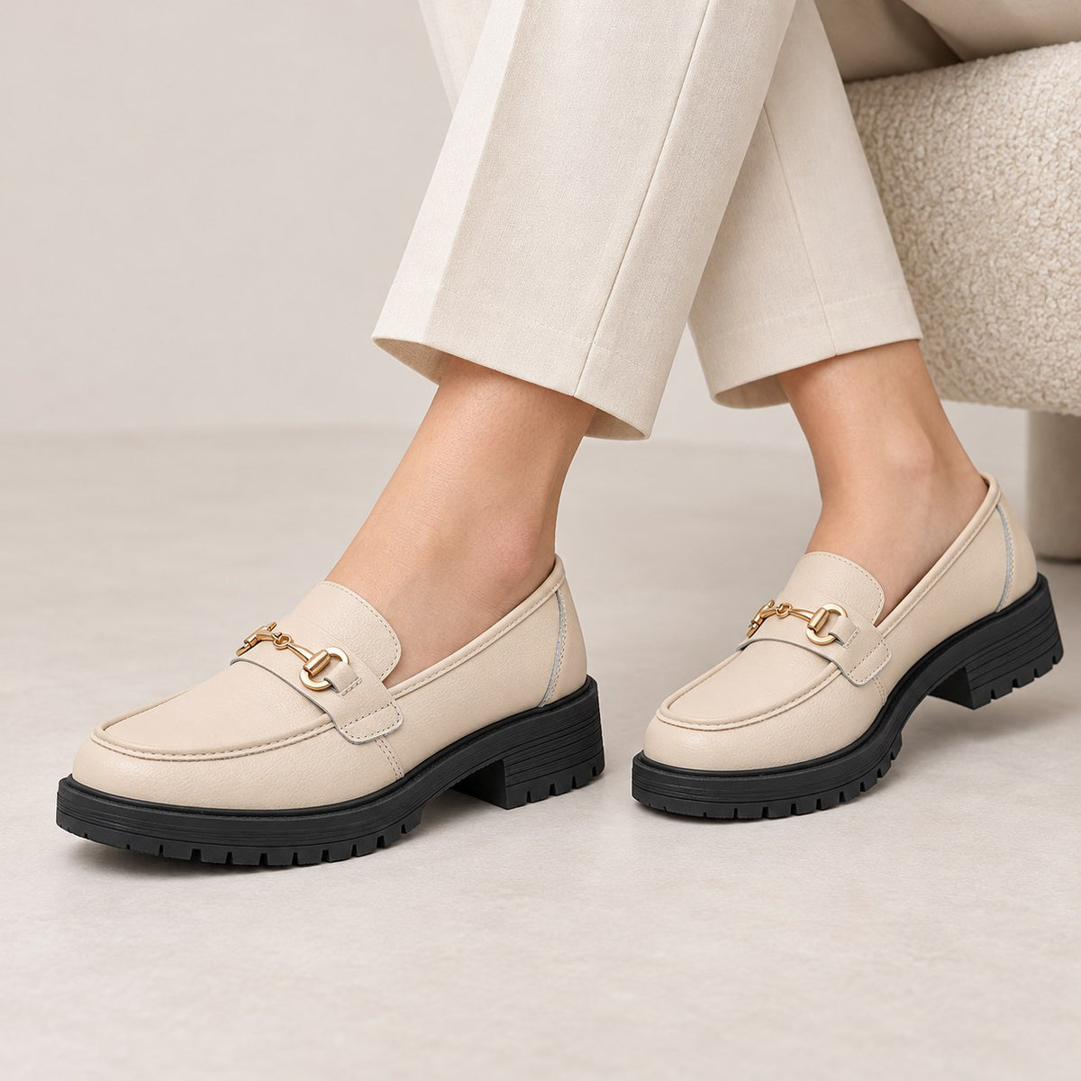 Mocasines beige con detalle metálico puestos con pantalón crudo