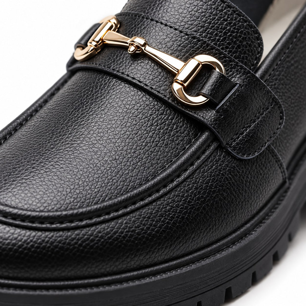 Detalle del herraje dorado y la piel granulada del mocasín negro