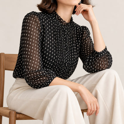 Blusa negra de gasa plumeti, sentada con pantalón crudo