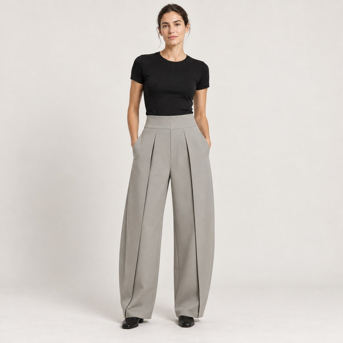Pantalón globo plisado gris claro con camiseta negra, de cuerpo entero