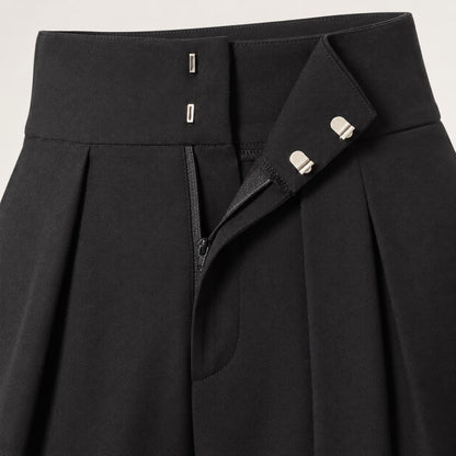 Detalle de la pretina, los corchetes y los pliegues del pantalón globo negro
