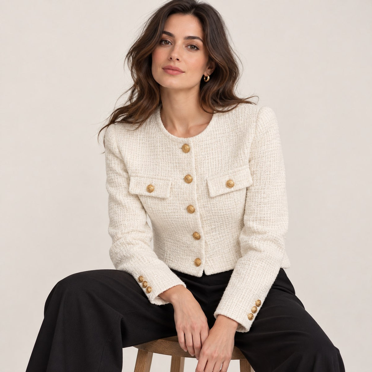 Chaqueta tweed blanca con pantalón negro, sentada