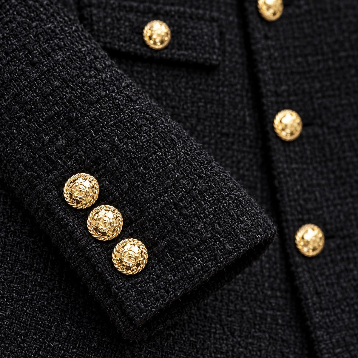 Detalle del tweed negro y los botones dorados del puño