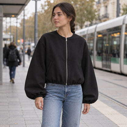 Chaqueta bomber cropped negra en una parada de tranvía