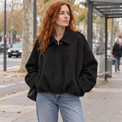 Chaqueta bomber de ante sintético negra en una avenida urbana
