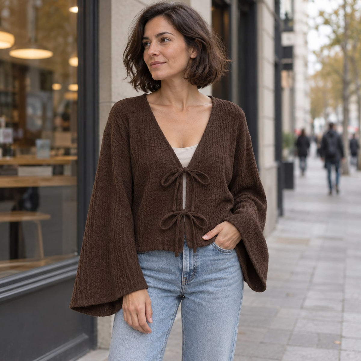 Blusa de punto café con lazada y mangas amplias en la ciudad
