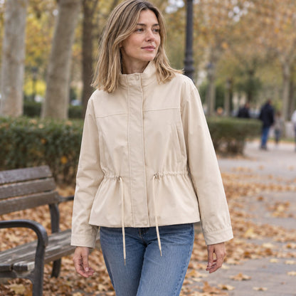 Chaqueta entretiempo beige con cuello alto y cordón en la cintura, parque urbano