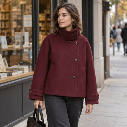 Abrigo corto de cuello alto burdeos junto a una librería urbana