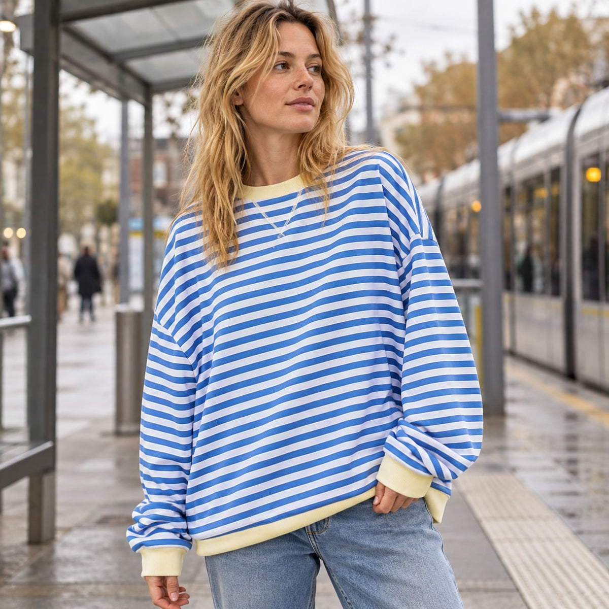 Jersey oversize de rayas azul y blanco con ribetes claros en una parada de tranvía
