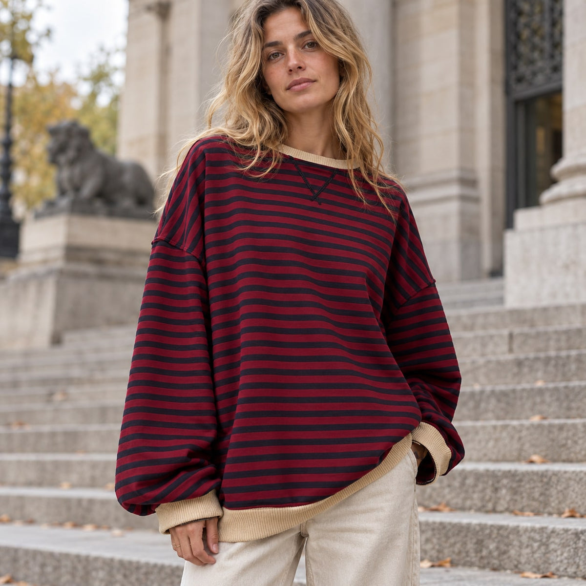Jersey oversize de rayas burdeos y negro con ribetes claros en escalinatas urbanas