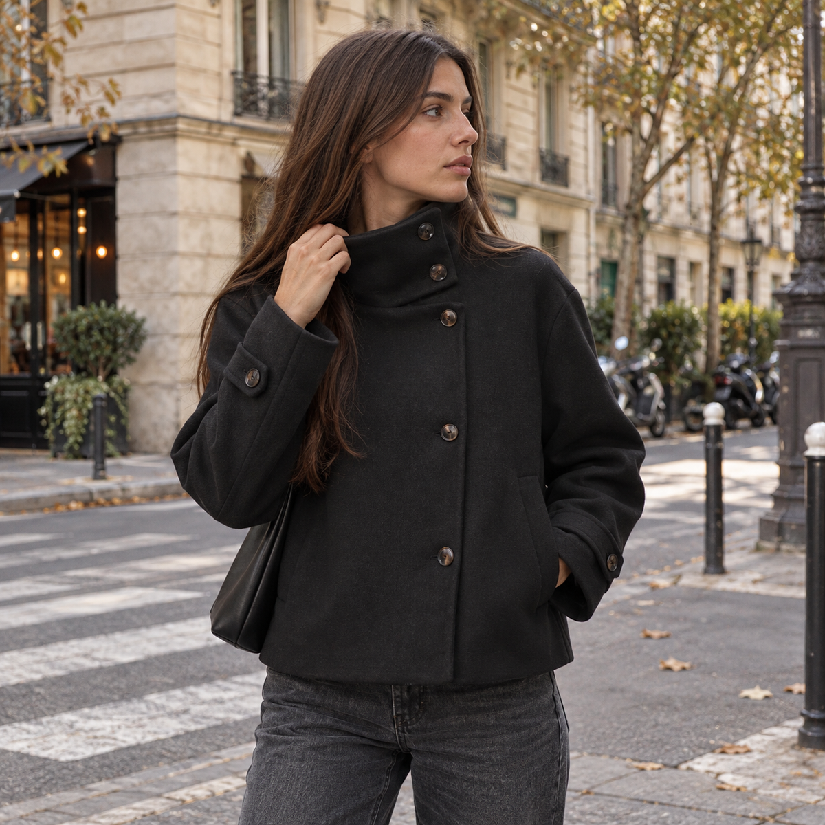 Abrigo corto negro de cuello alto con botones asimétricos, look de otoño