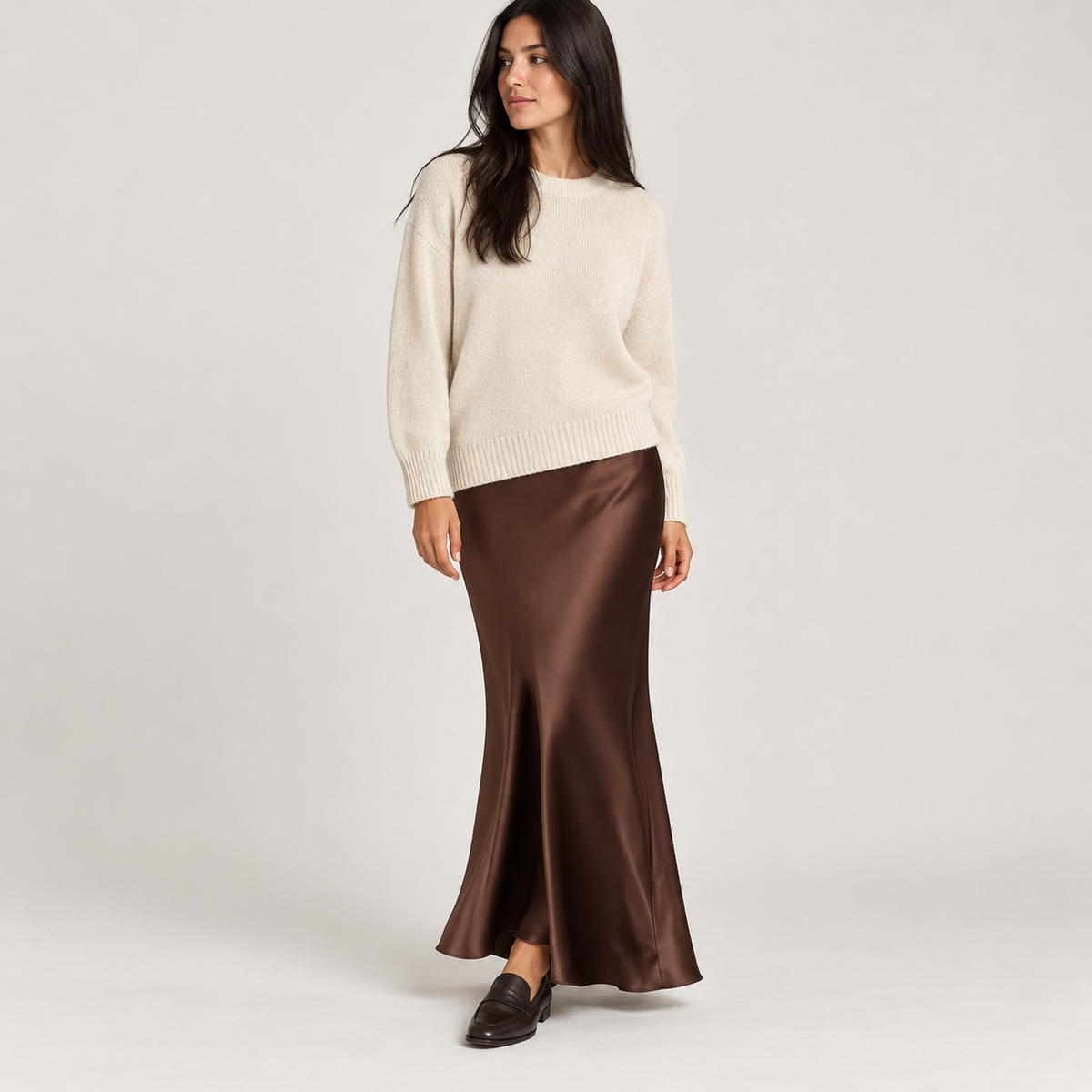 Falda larga satinada marrón oscuro con jersey crema, foto de estudio