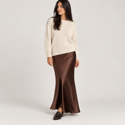 Falda larga satinada marrón oscuro con jersey crema, foto de estudio