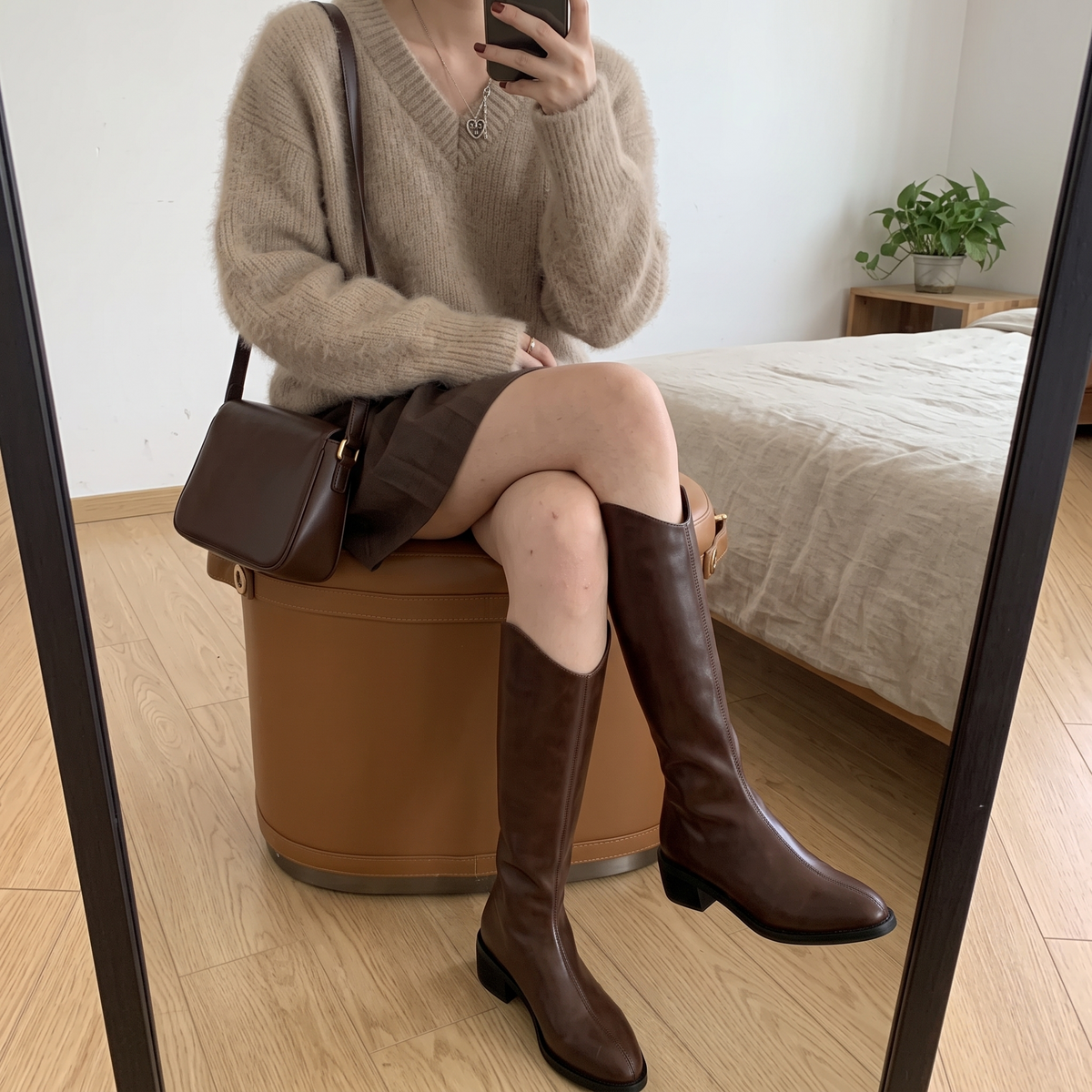 Botas altas marrones con costura central puestas, foto real en casa